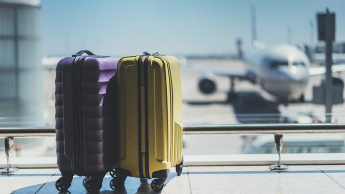 Two suitcases in the airport departure lounge, airplane in the blurred background, summer vacation concept, traveler suitcases in airport terminal waiting area