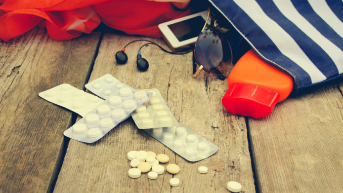 Summer women's beach accessories for your sea holiday and pill on old wooden background. Concept of medication required in journey. Toned image.