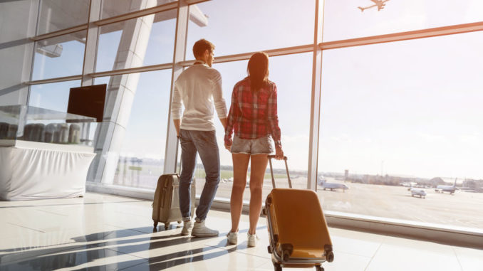 Young man and woman looking at flying plane