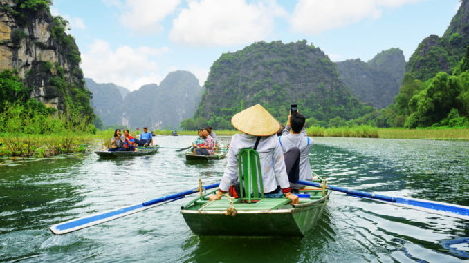Tourists traveling in small boat along Ngo Dong River, Vietnam