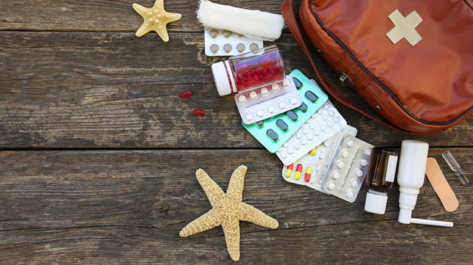 First aid kit on old wooden background. Concept of medication required in journey. Top view. Flat lay.