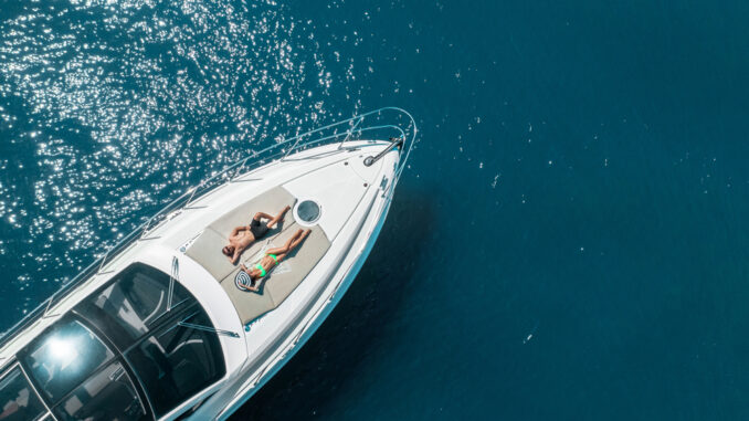 Aerial,View,Of,Couple,Enjoying,Sunbathing,On,The,Luxury,Yacht