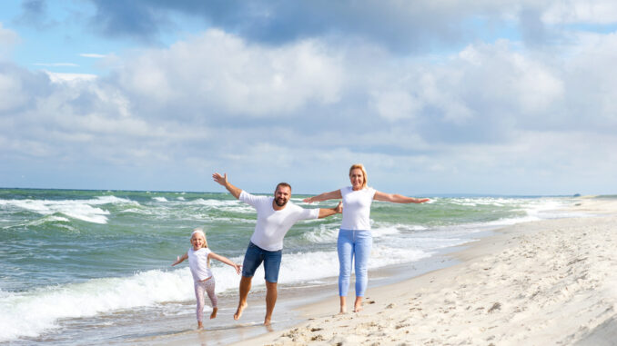 A,Little,Girl,And,Her,Parents,Walk,On,The,Beach